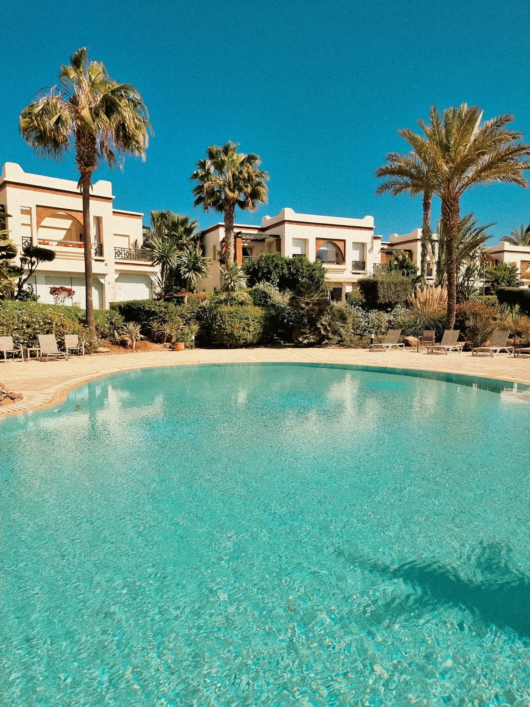 Grande piscine entourée de palmiers et de villas à Agadir, au Maroc